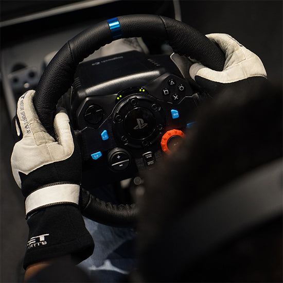 Logitech G29 black racing wheel with blue accents, held by gloved hands.