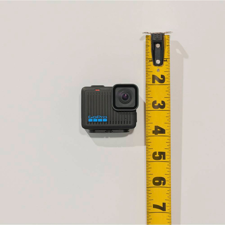 Black GoPro Hero action camera next to yellow tape measure on white background