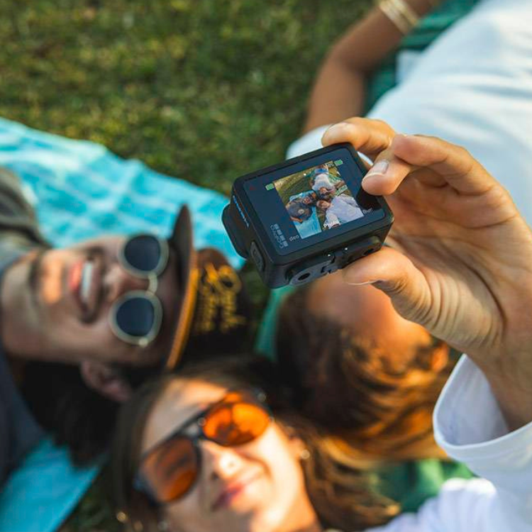 Black GoPro action camera displaying photo of smiling people on screen.