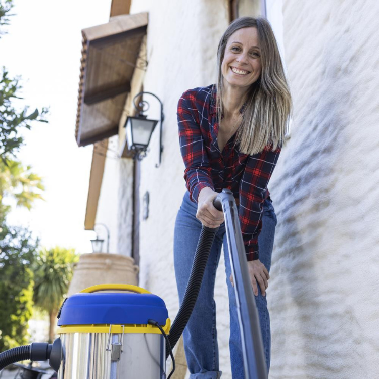 Aspirador de sólidos e líquidos Goodyear GY12VC 20L azul e amarelo com mulher ao lado.