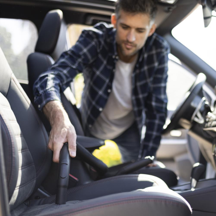 Aspirador de sólidos e líquidos Goodyear GY12VC, 20L, preto, sendo usado por um homem a limpar o interior de um carro.