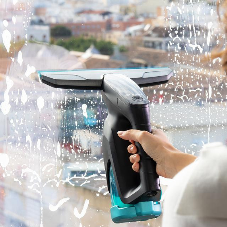 Aspirador de vidros Cecotec Conga Popstar Glass Titânio, com base azul e corpo preto, sendo segurado por uma mão junto a uma janela suja com gotas de água.