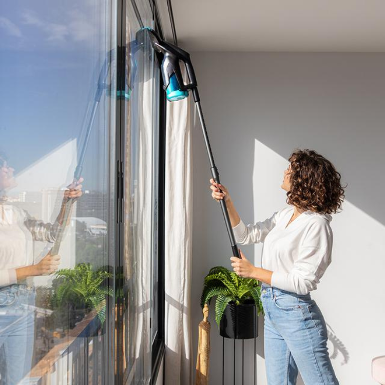 Mulher a limpar janela com aspirador de vidros Cecotec Conga Popstar Glass Titânio.