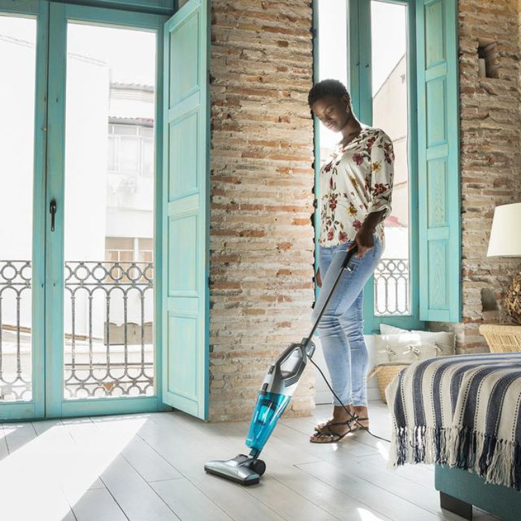 Woman using Cecotec Conga Popstar 1000 Duostick blue upright vacuum cleaner.