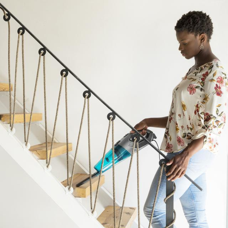 Woman using Cecotec Conga Popstar 1000 Duostick vacuum on stairs.