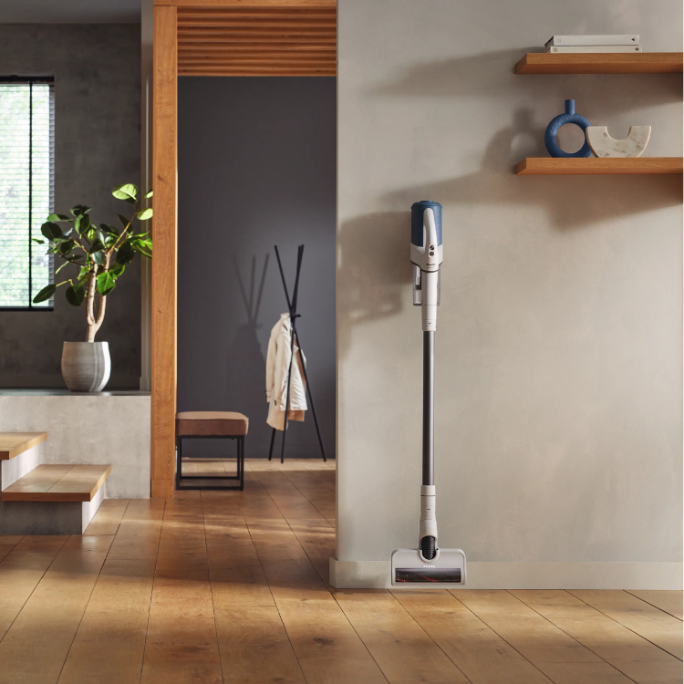 Aspirador vertical Miele Duoflex HX1 azul apoiado numa divisão moderna.