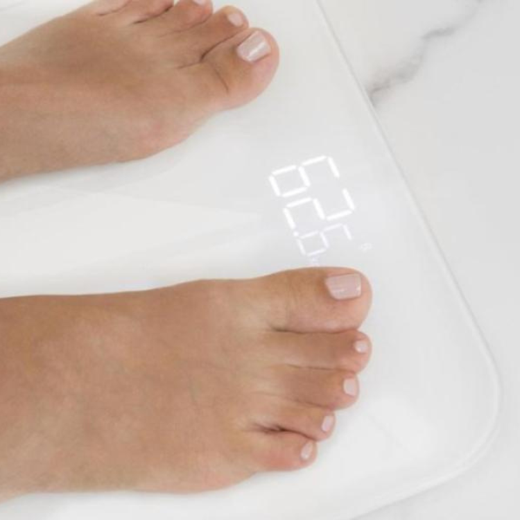 White digital bathroom scale with feet on it, displaying 55, Cecotec brand.