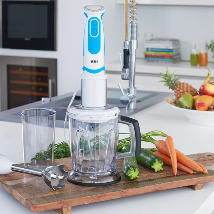 Braun MultiQuick 5 Vario 1000W white and blue handheld blender with attachments and vegetables on a wooden board.