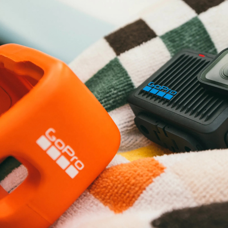 GoPro Floaty orange accessory and black HERO camera on towel.