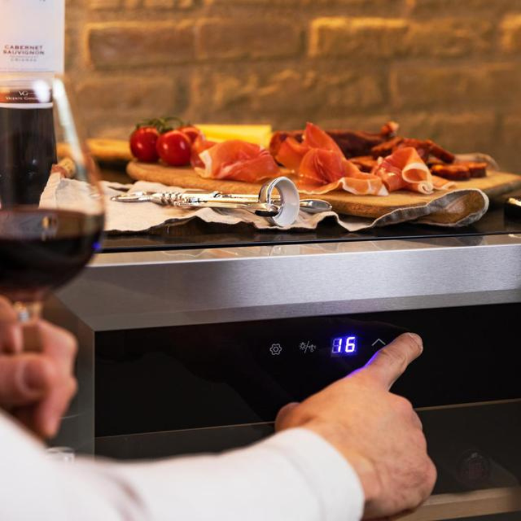 Cecotec Bolero GrandSommelier 2050 wine cooler with digital display set to 16, holding wine glass and charcuterie board nearby.