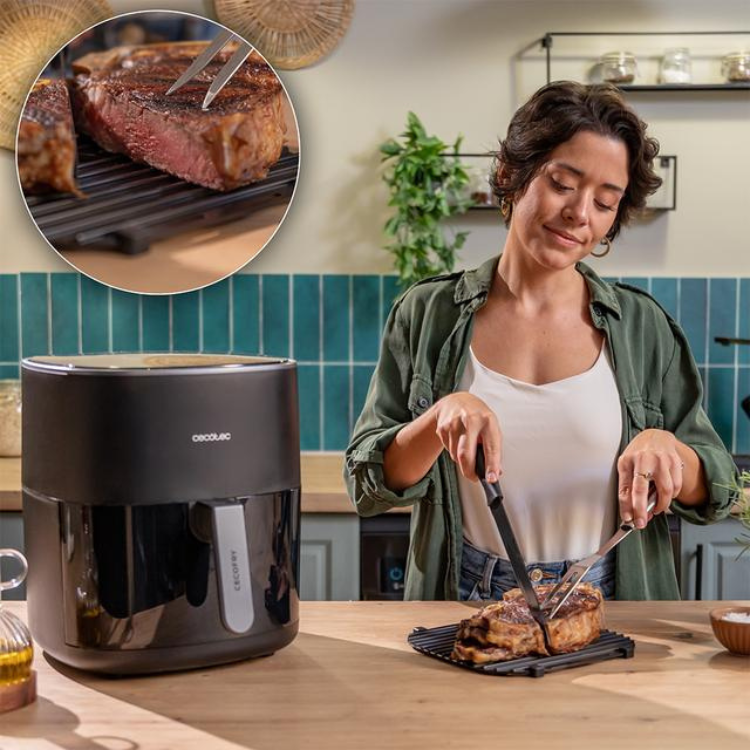 Black Cecotec air fryer, woman cutting meat on grill plate.
