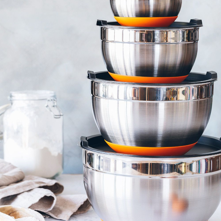 Stainless steel bowl set with 4 pieces, orange and black accents, stacked on top of each other.