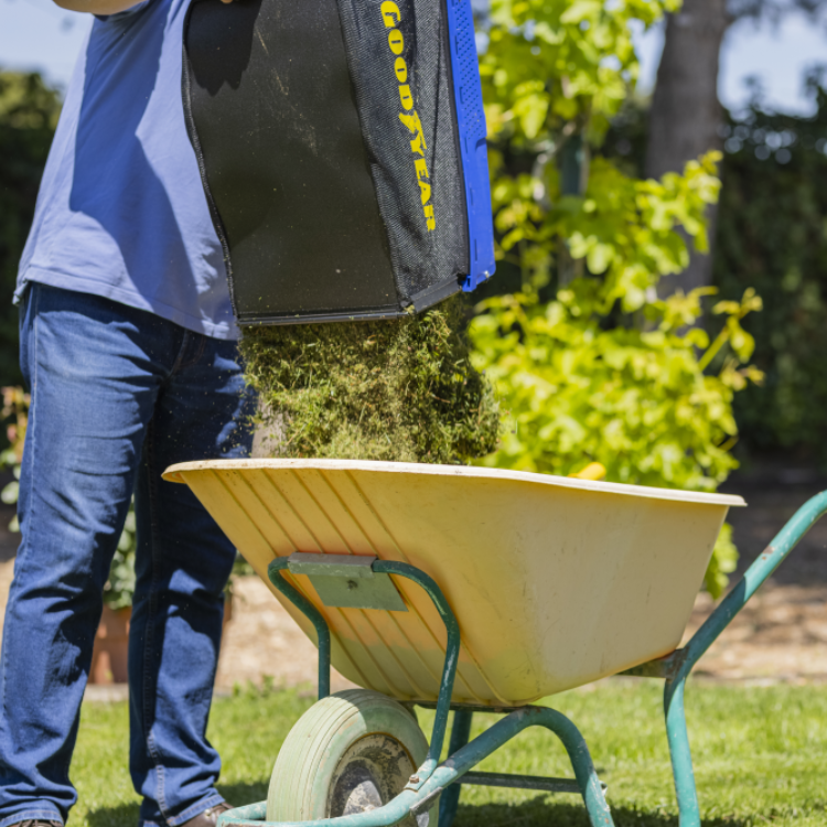 Goodyear black and blue lawn mower grass bag on wheelbarrow.