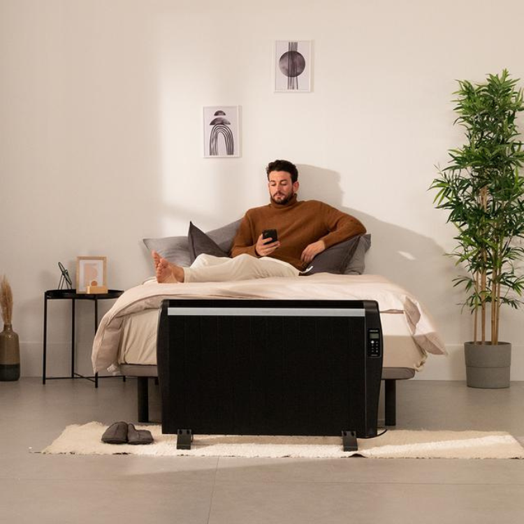 Black Cecotec Ready Warm 2500 Thermal heater on beige rug beside bed.