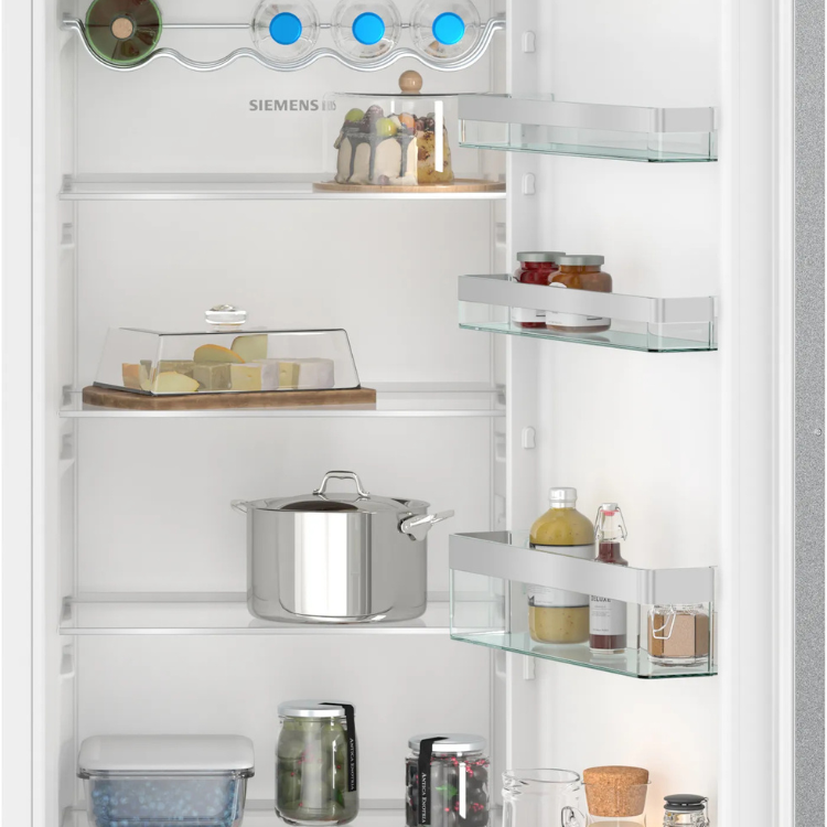 Siemens white built-in fridge interior with glass shelves and various food containers.