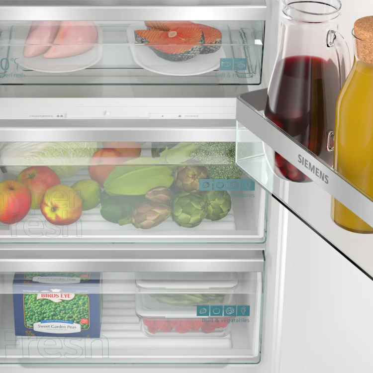 Siemens 310L white built-in fridge with open drawer showing fresh food storage.