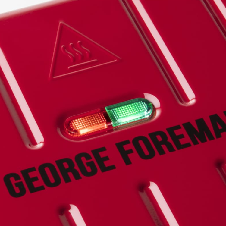 Red George Foreman grill with heat indicator lights and warning symbol.