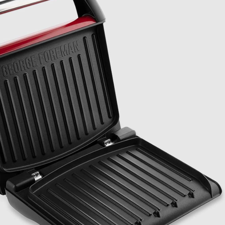 Red George Foreman electric grill, open, showing black grill plates.