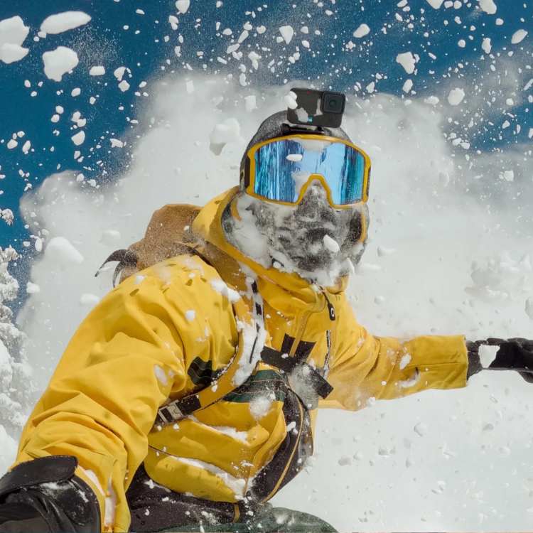 GoPro Head Strap 2.0 on a snowboarder's helmet, yellow jacket, blue goggles.