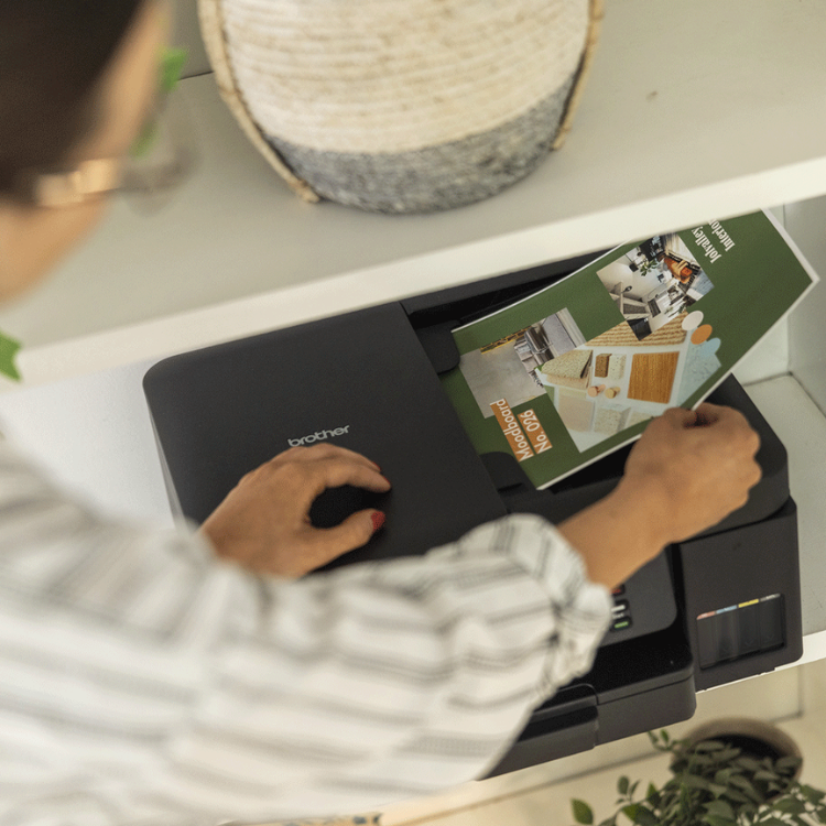 Black Brother DCP-T780DW inkjet multifunction printer with person scanning document.