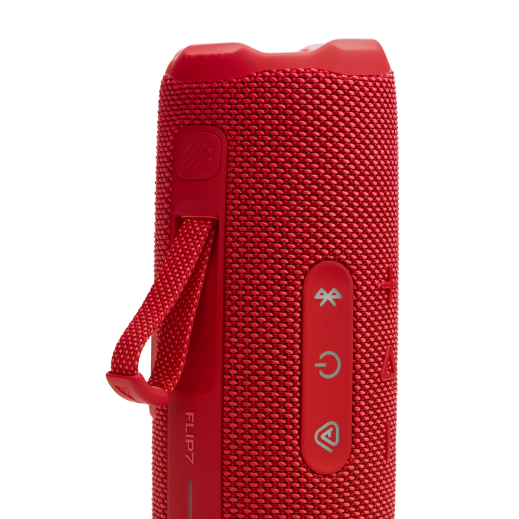 Red JBL Flip 7 portable speaker with buttons and strap.