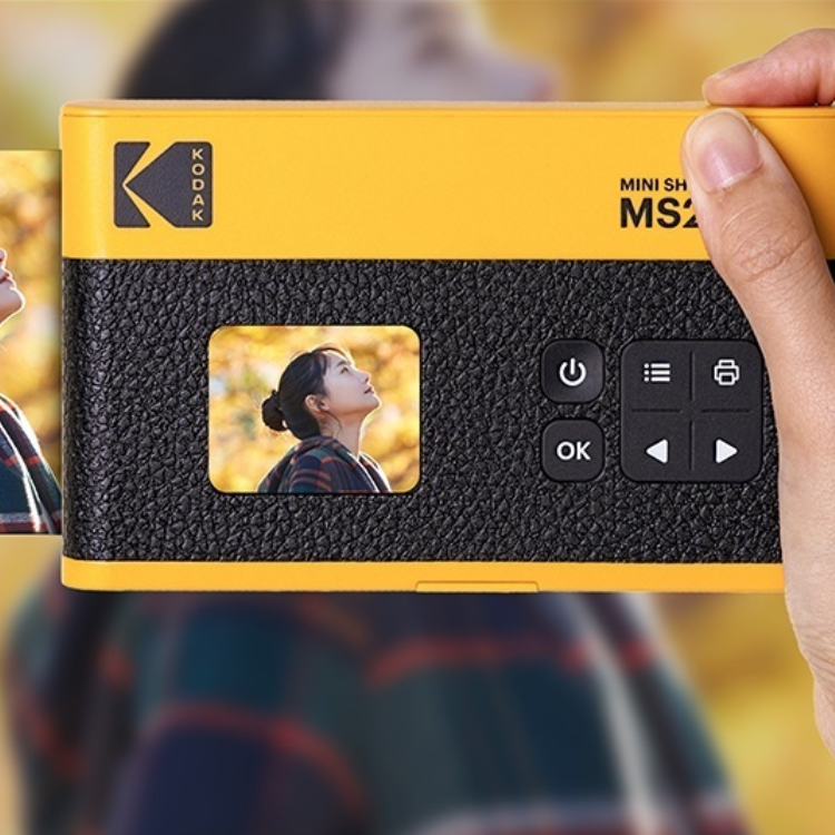 Yellow Kodak Mini Shot 2 Era MS200 instant camera, black textured body, LCD screen showing woman outdoors.