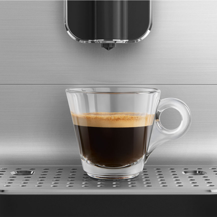Black coffee in a clear mug on a Smeg automatic coffee machine.