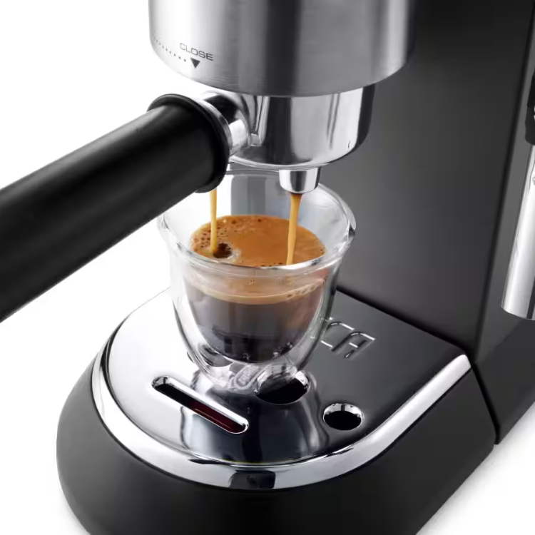 De'Longhi Dedica espresso machine dispensing coffee into a clear cup. Black and silver.