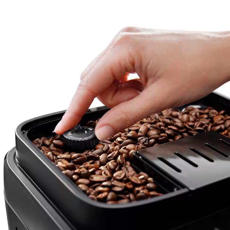 Black coffee bean container with brown beans, finger adjusting grind setting on Delonghi Magnifica Evo machine.