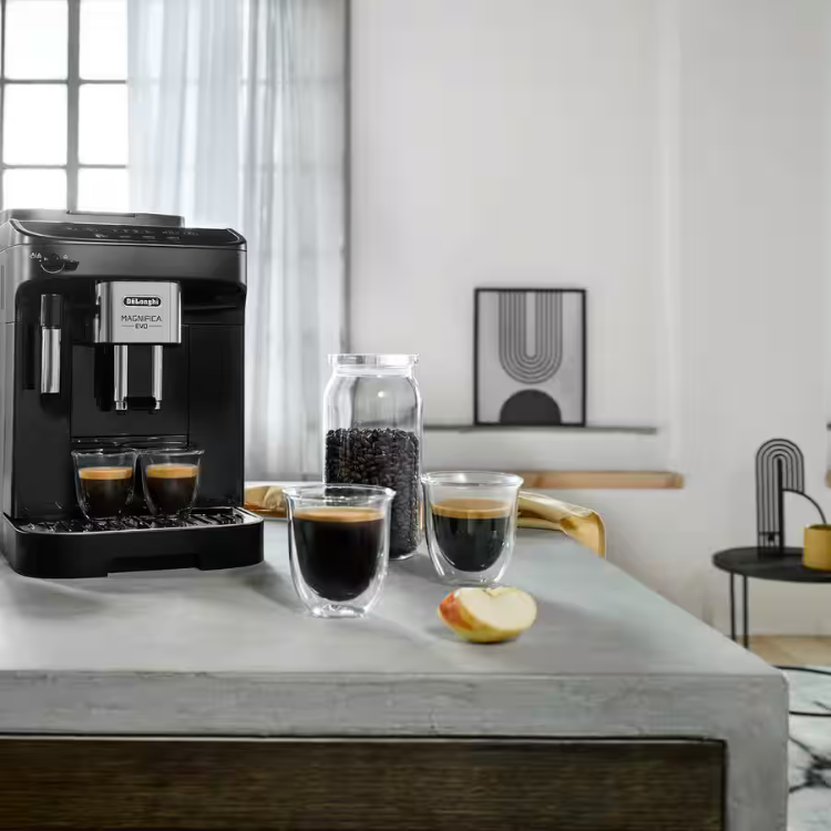 Black De'Longhi Magnifica Evo automatic coffee machine on gray countertop with three cups of coffee and coffee beans.