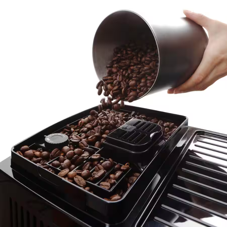 Black coffee bean container being poured into Delonghi Magnifica Start LatteCrema coffee machine.