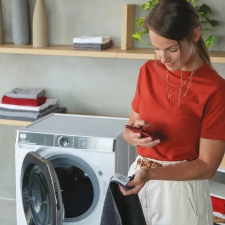 White Hoover washer dryer, 8kg/5kg, 1400RPM, Class D. Woman checking phone.