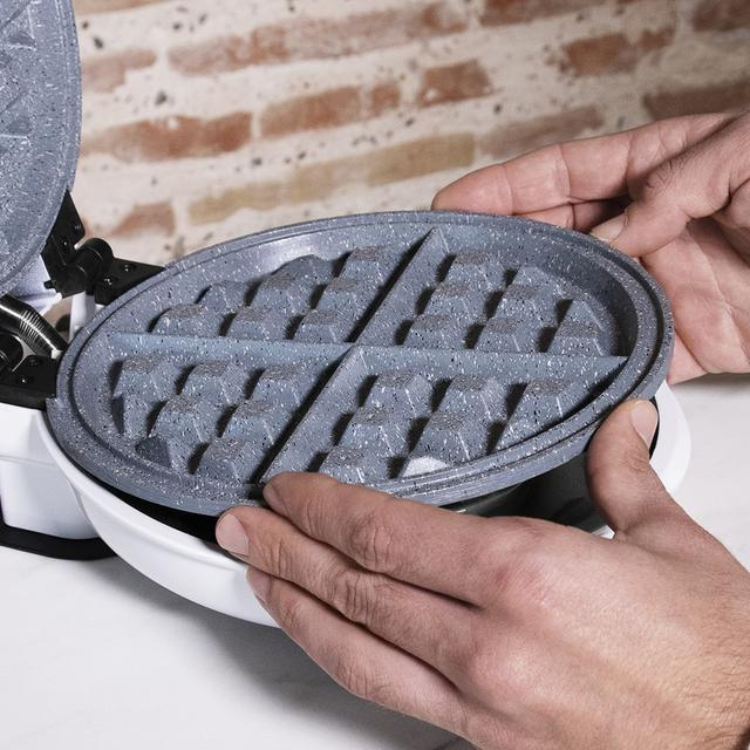 Cecotec Fun Gofrestone 3-in-1 waffle maker, white base, gray non-stick plates, hands holding plate.