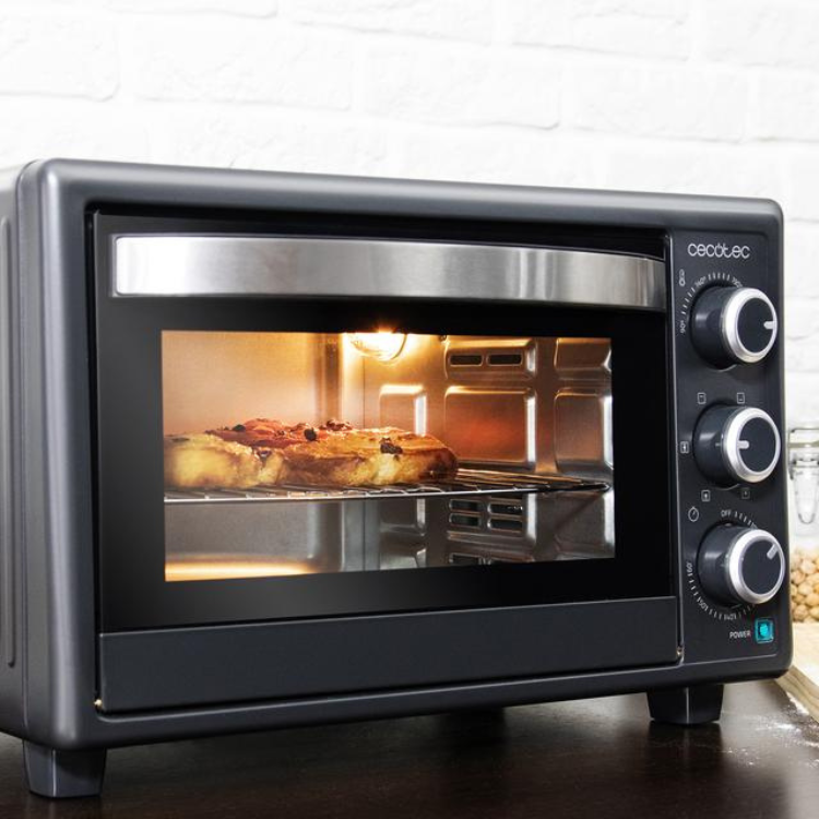 Black Cecotec mini oven with silver accents and knobs, glass door showing bread inside.