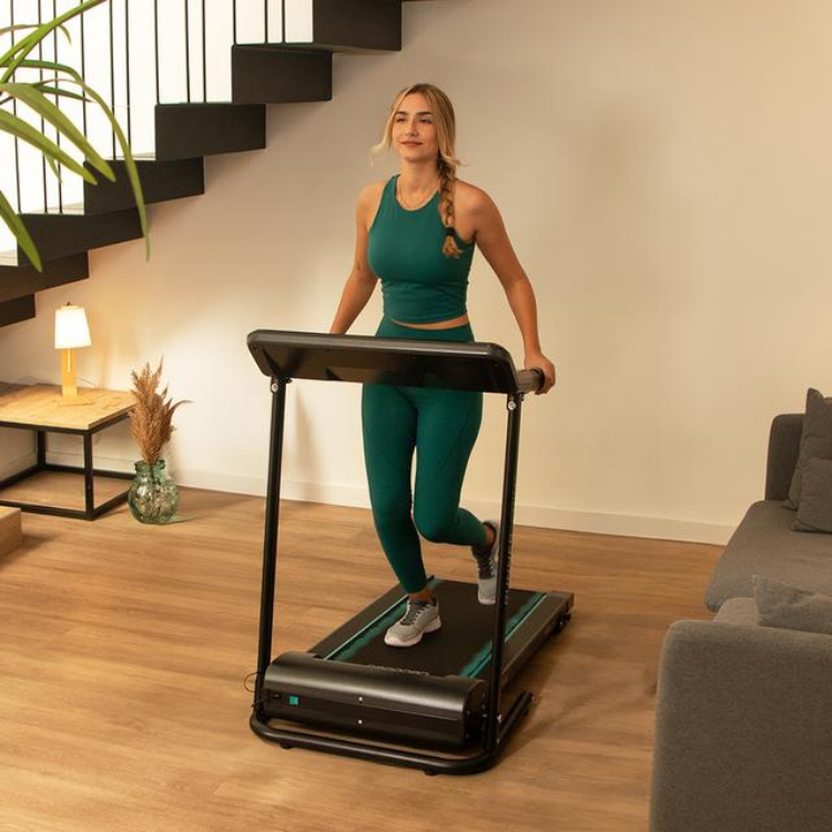 Woman exercising on black Cecotec DrumFit WayHome 1000 Runner Sprint treadmill in living room.