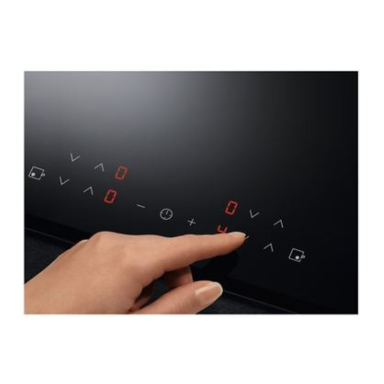 A hand pressing a button on a black induction cooktop control panel with red and white symbols.