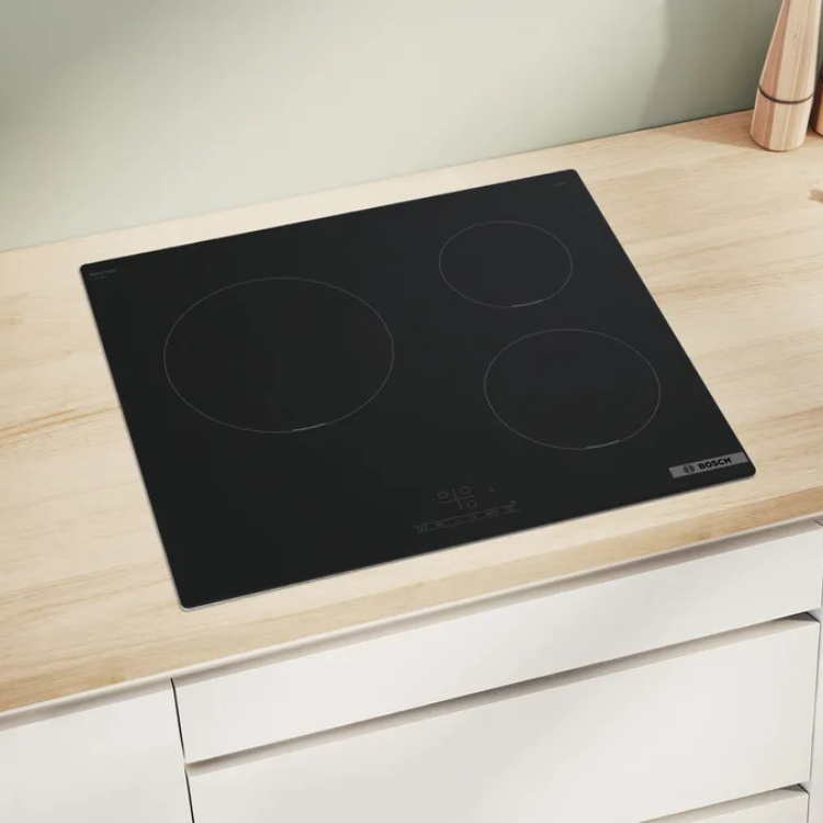 Black induction cooktop, Bosch, 3 zones, on light wood countertop.