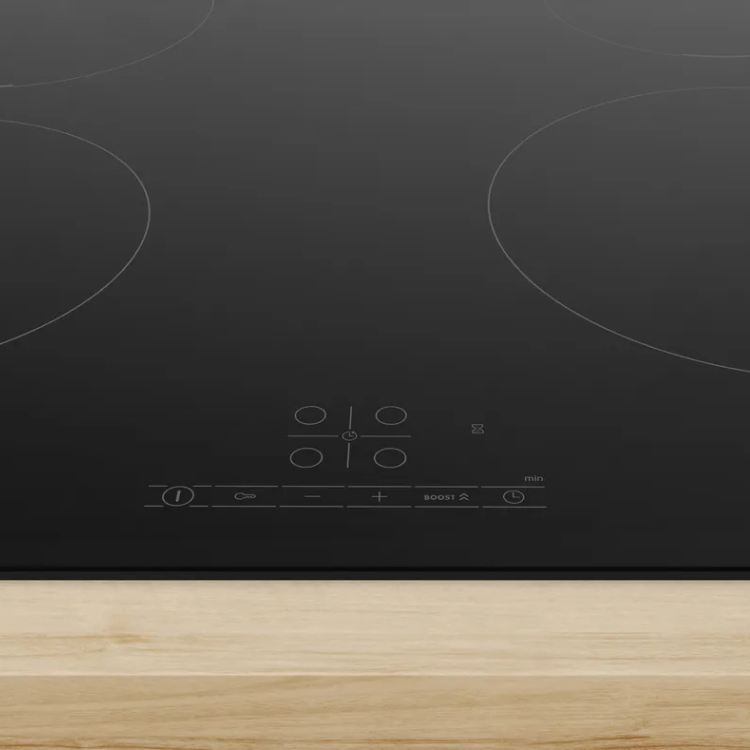 Black induction cooktop with 4 zones, white controls, on light wood surface, Bosch Serie 4.