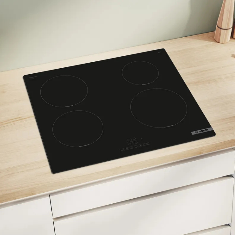 Black Bosch induction cooktop with 4 zones on light wood countertop.