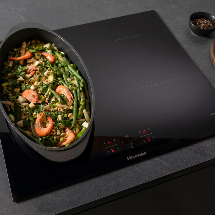 Black Hisense induction cooktop with red display and 4 zones, cooking shrimp and vegetables.