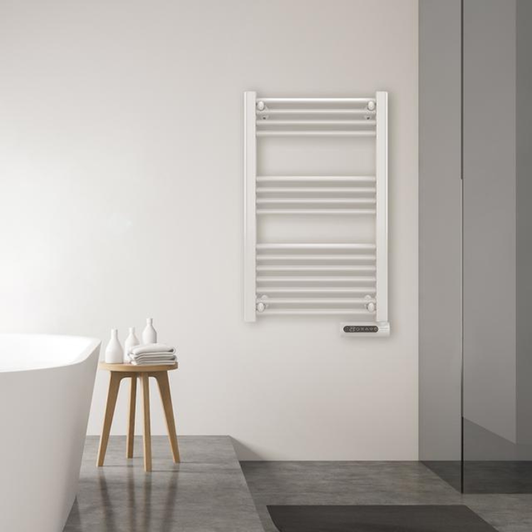 Toalheiro Elétrico Cecotec Ready Warm 9100 Smart Towel branco montado na parede de uma casa de banho, ao lado de uma banheira e um banco com toalhas.
