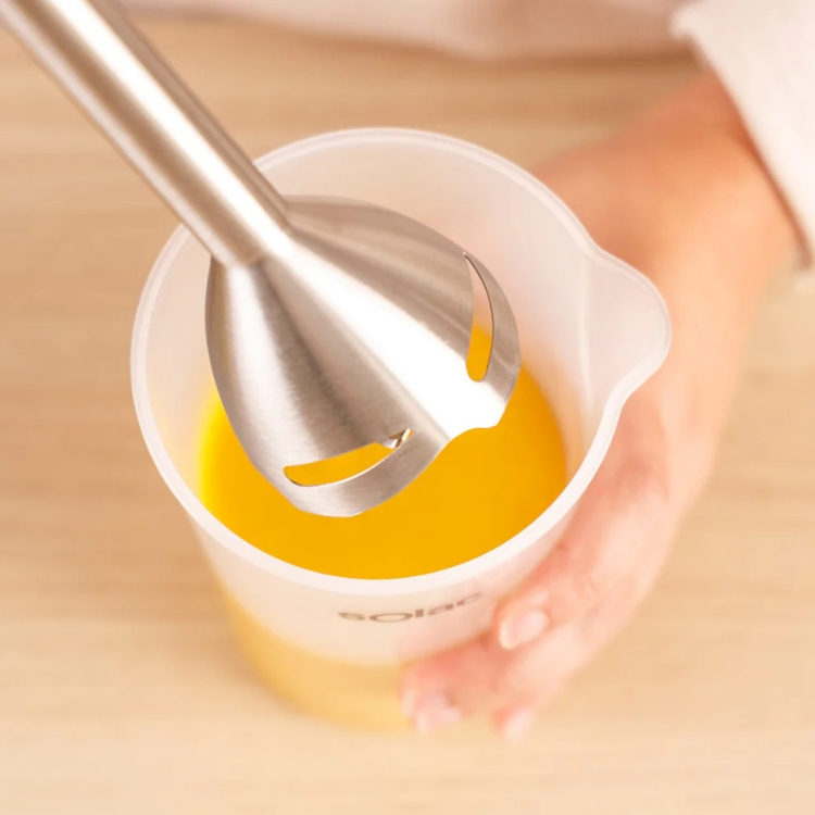 Solac Pro Chef 1501 inox handheld blender in stainless steel and white, blending yellow liquid.